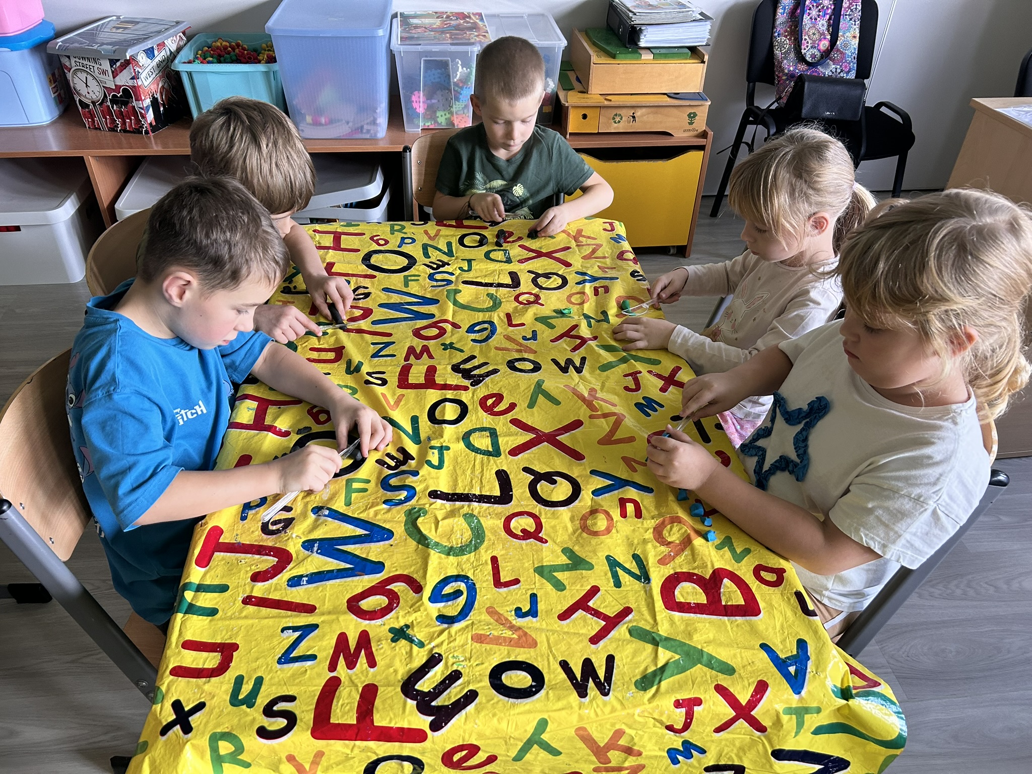 Dzieci kroją plastelinę plastikowym nożem.