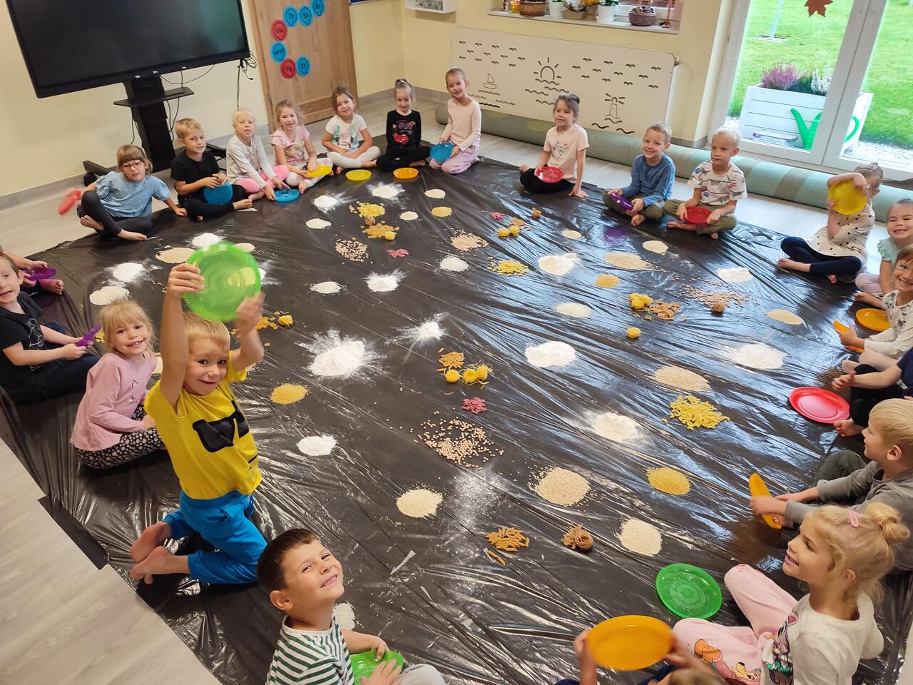 Dzieci siedzą zaciekawione zajęciami.