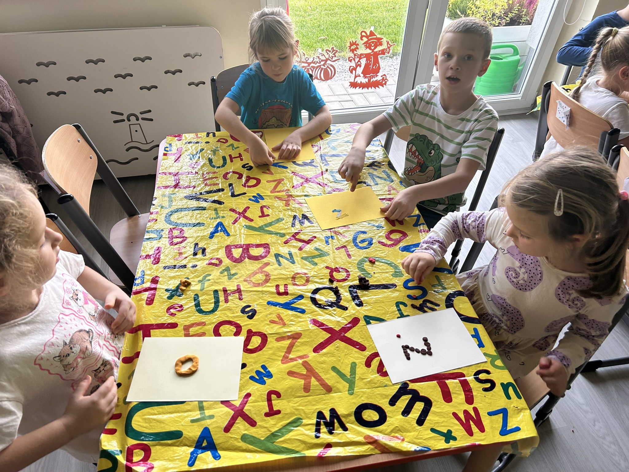 Dzieci wyklejają plasteliną swoją literkę imienia.