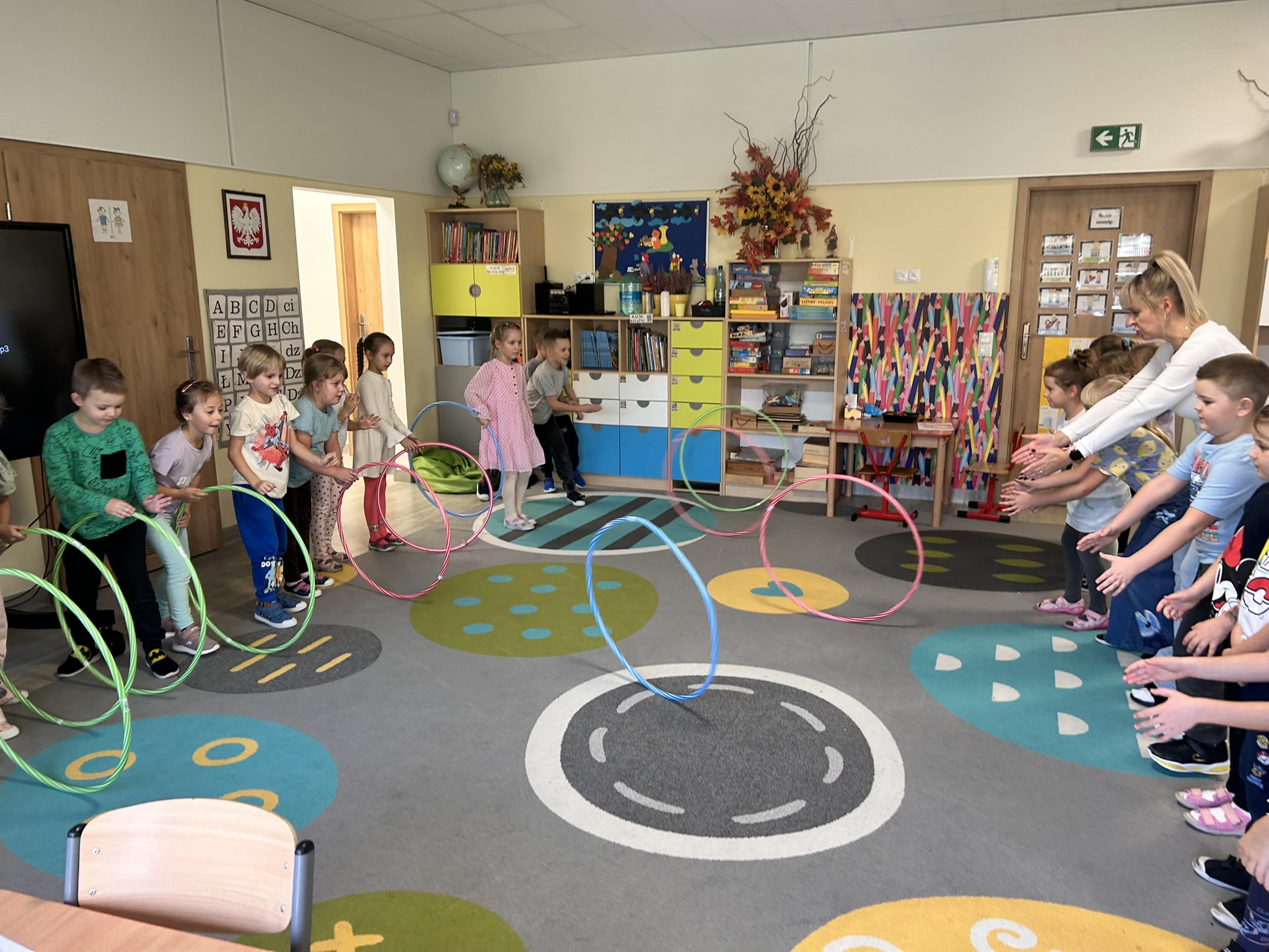 Dzieci podają do siebie hula-hop.