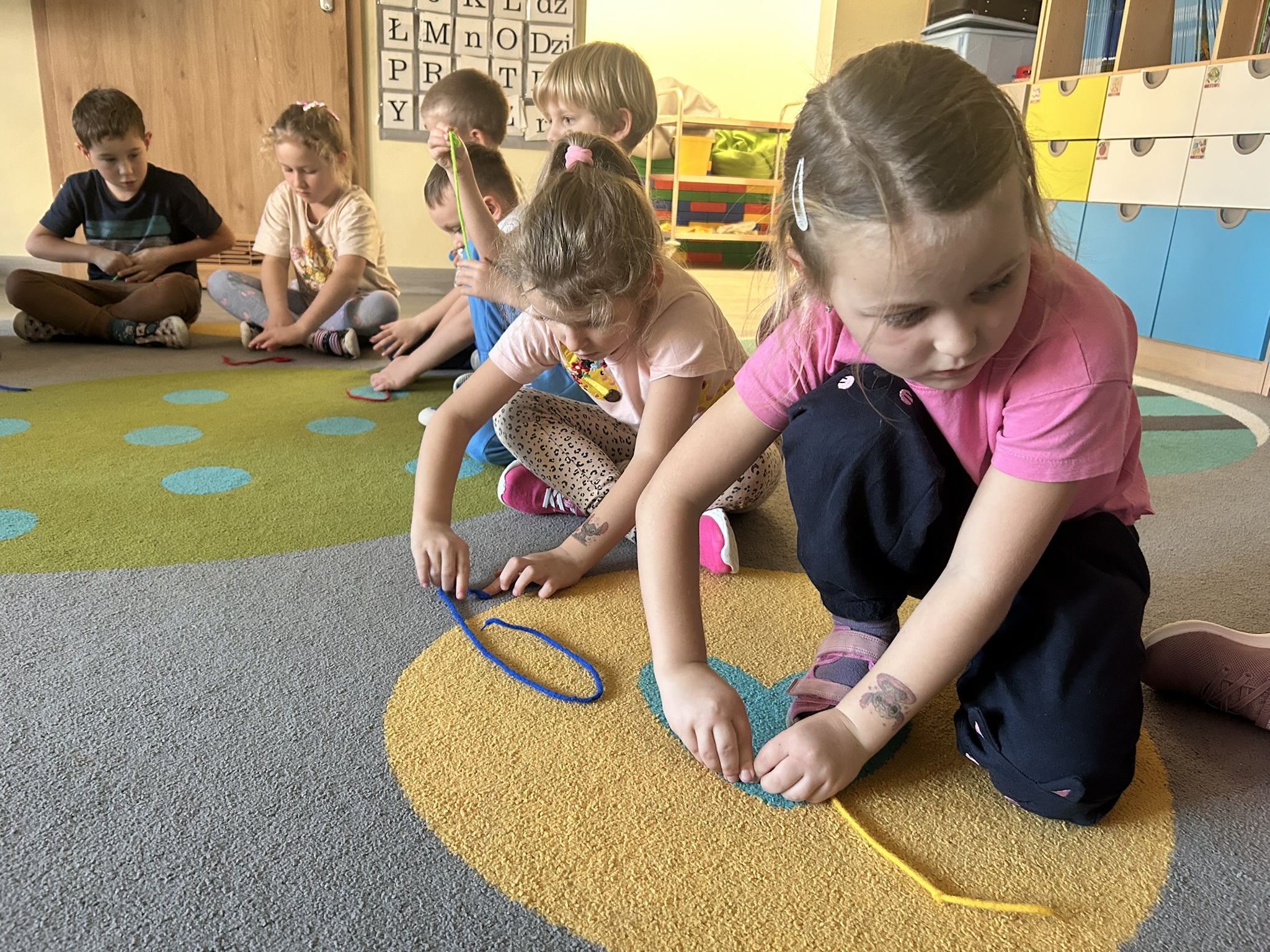 Dzieci zwijają ślimaka ze sznurka.