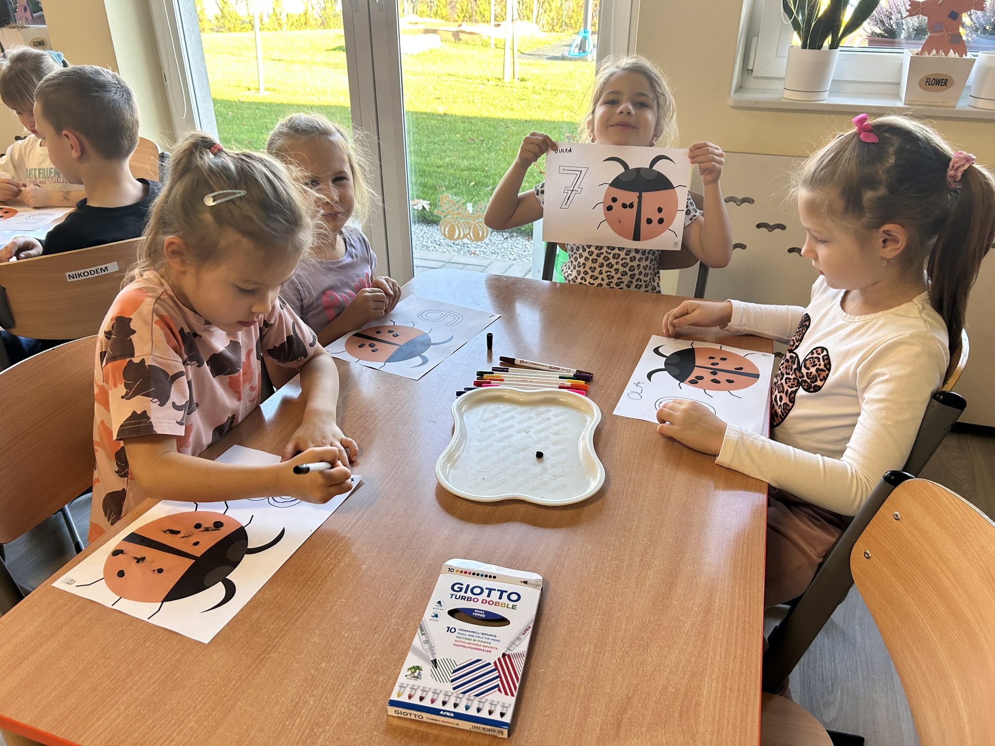 Przedszkolaki wyklejają kropki biedronce.