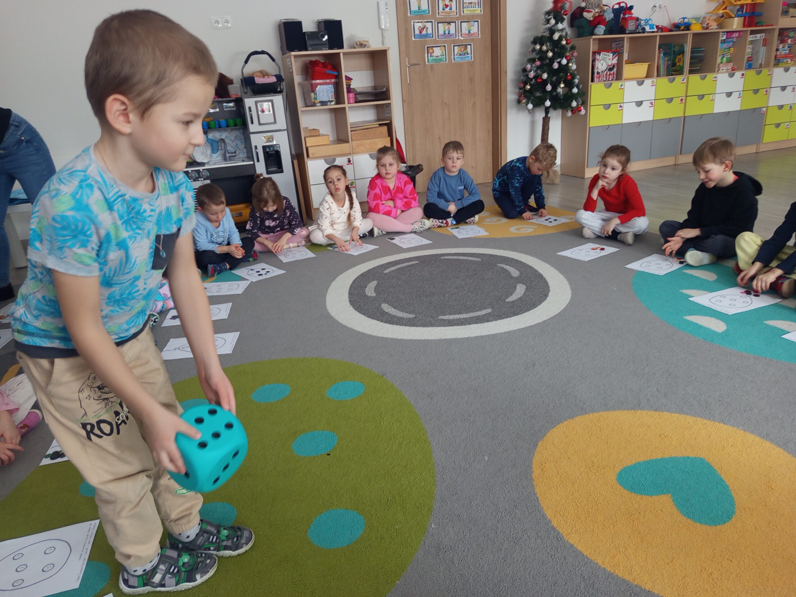 Chłopiec rzuca kostką i losuje ćwiczenie do wykonania.