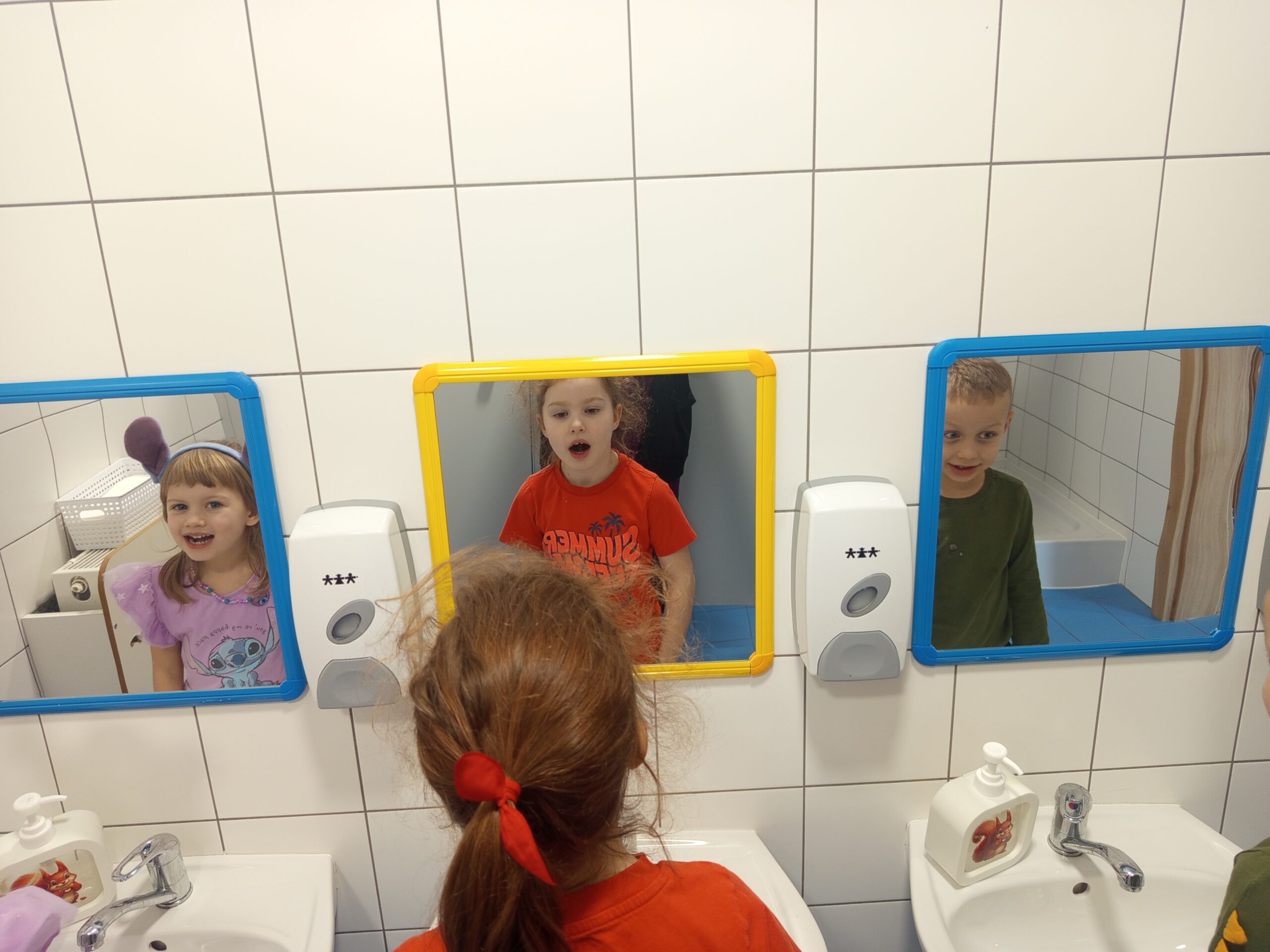 Dzieci ćwiczą tzw. glonojada przed lustrem.