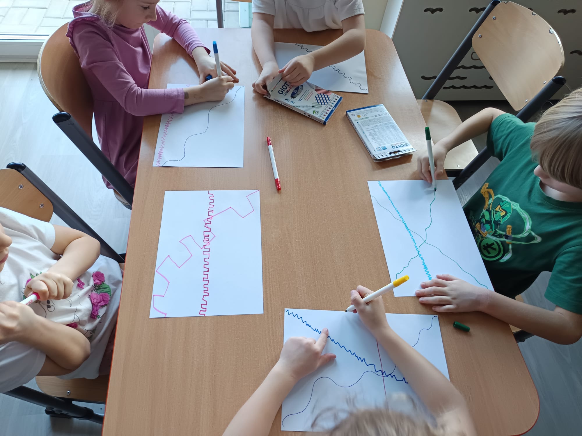 Dzieci rysują linie mazakami.