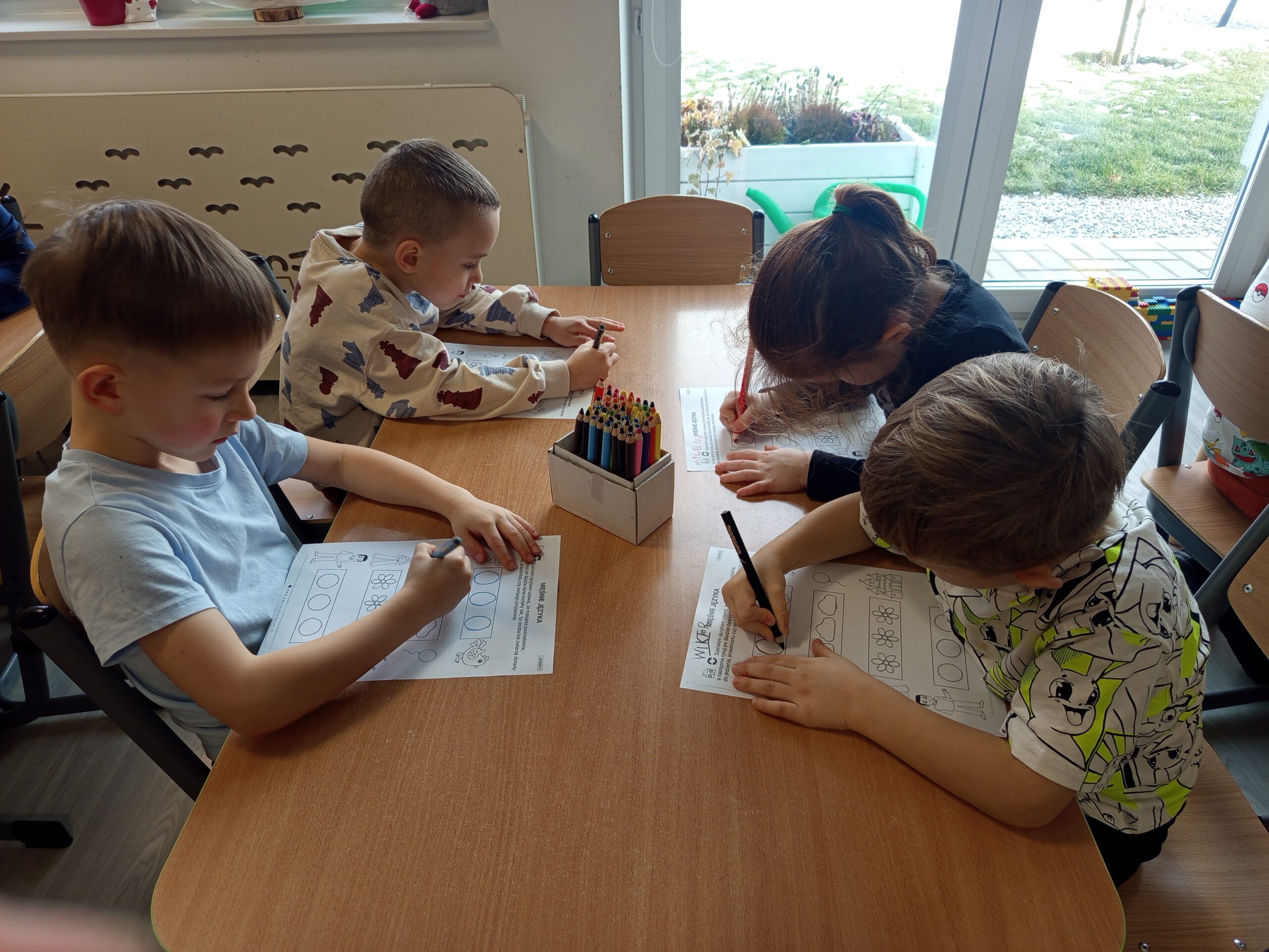 Dzieci wykonują kartę pracy z ćwiczeniem języka