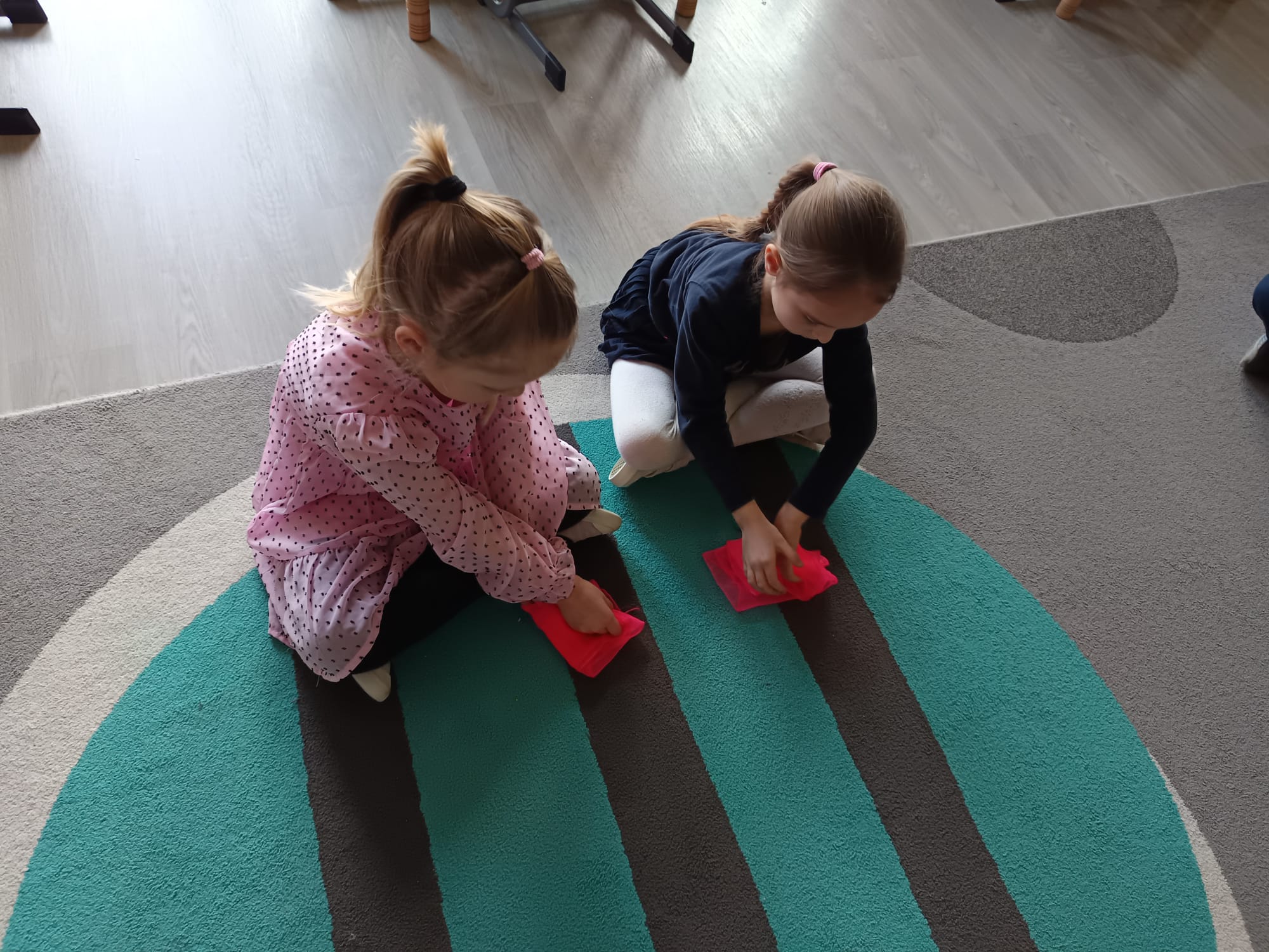 Dziewczynki składają chustkę w kostkę.