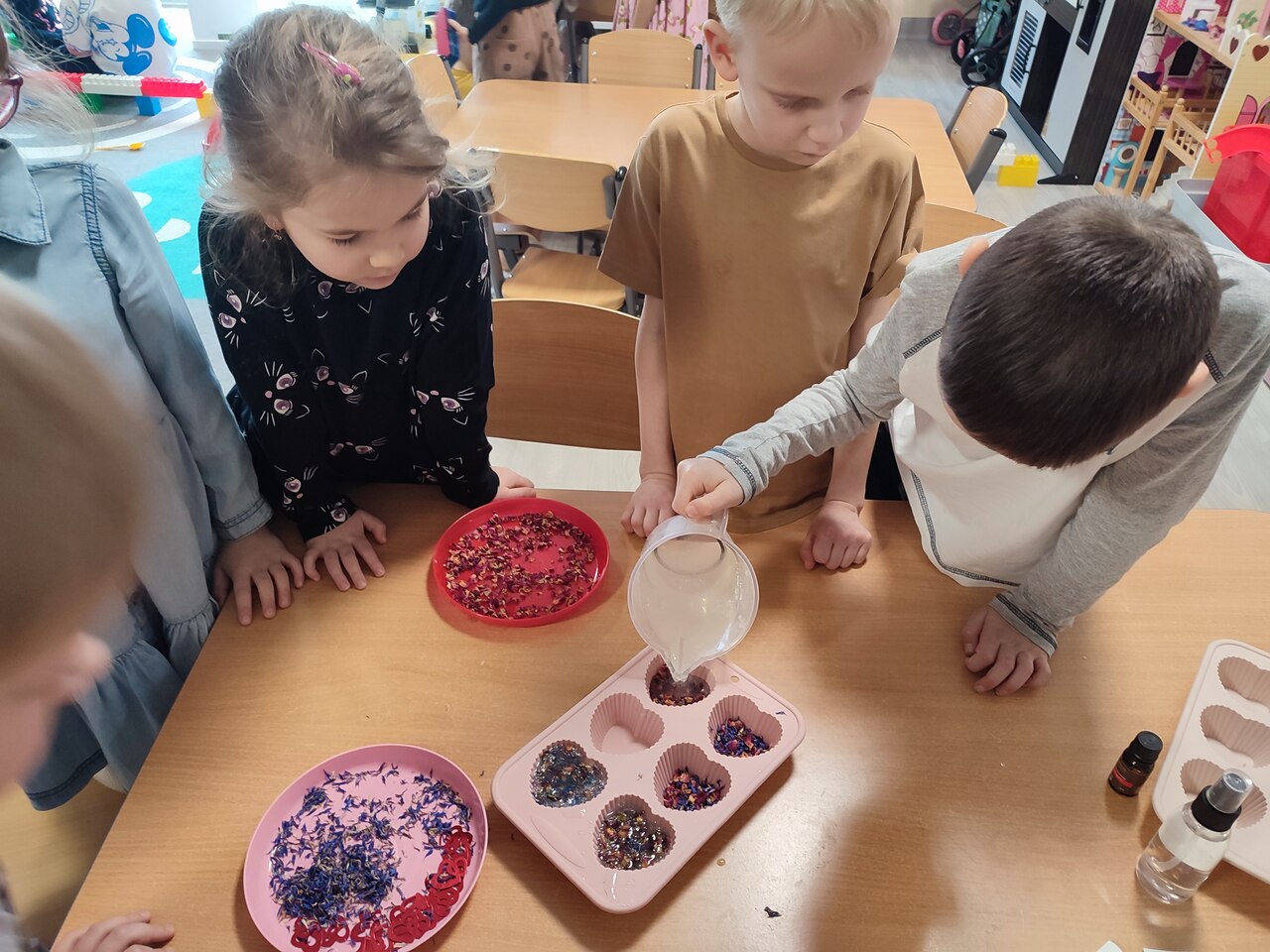 Dzieci zalewają kwiatowe kompozycje.