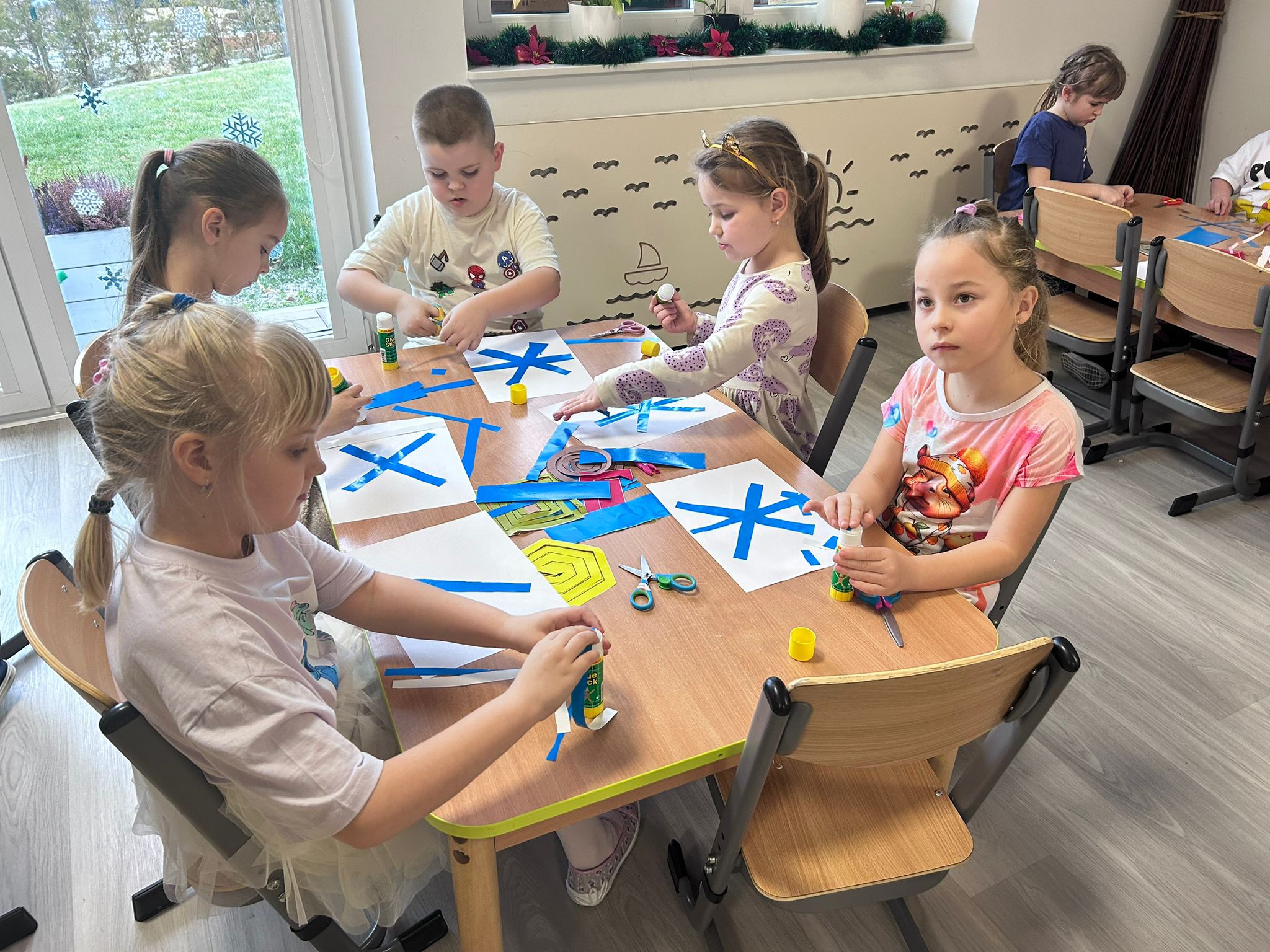 Dzieci wykonują pracę plastyczną pt. "Śnieżynki"
