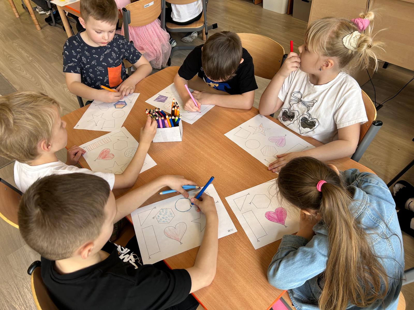 Dzieci kolorują nartkach kształty.